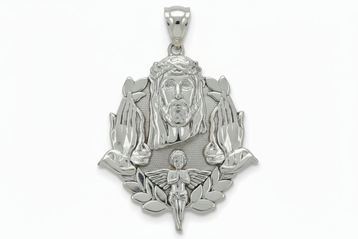 A silver pendant featuring a detailed depiction of Jesus Christ with a crown of thorns, flanked by praying hands and a small angel at the bottom, shown against a plain light gray background.