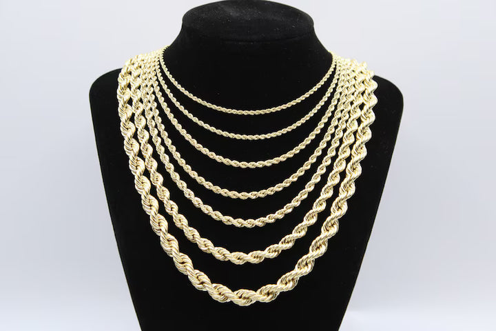 Gold chain necklaces displayed on a black mannequin bust.